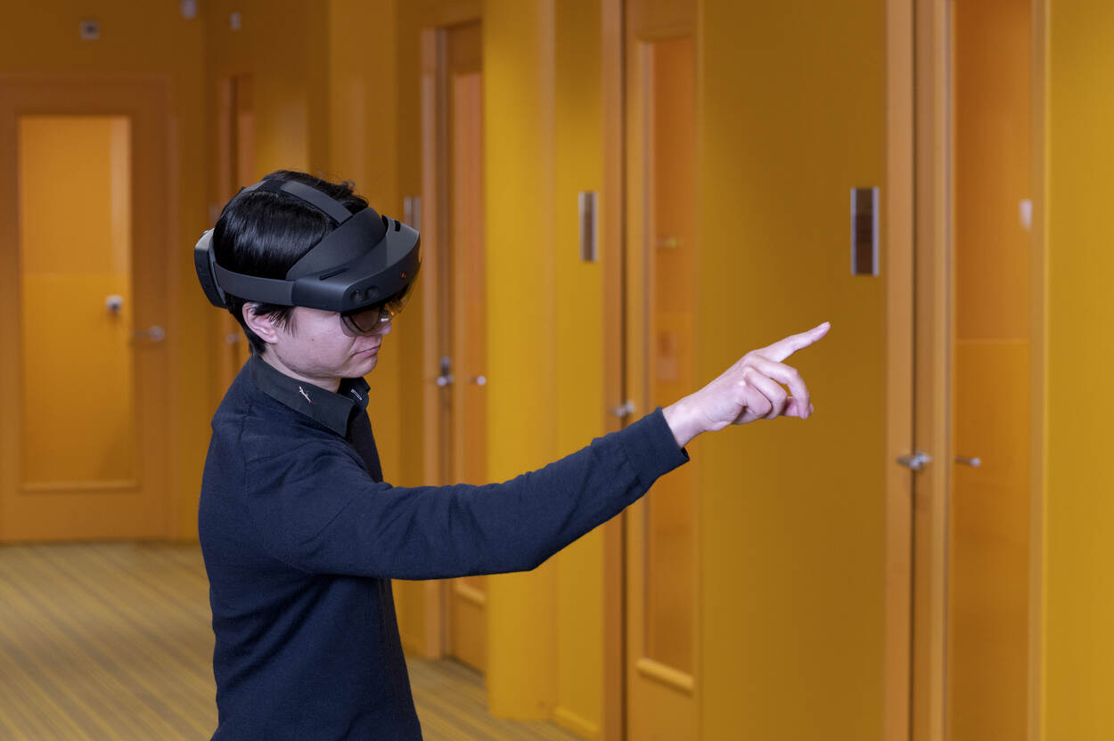 Young person wearing VR-glasses is pointing in the air